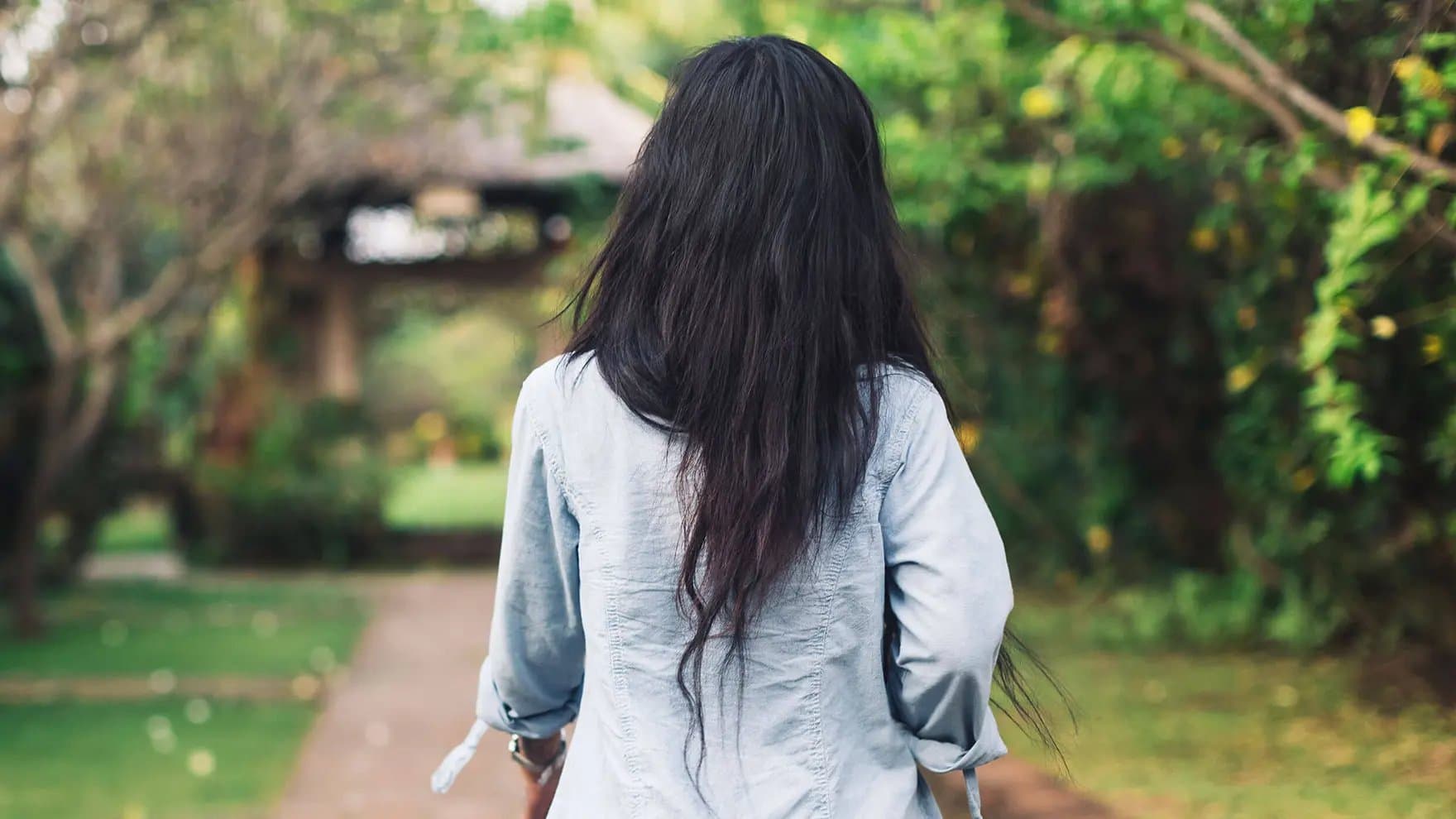 Woman with long, dark hair in a blue shirt with her back turned to the camera