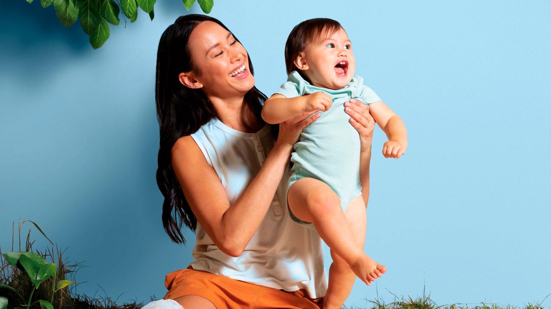 A mother holds up her baby and they both smile